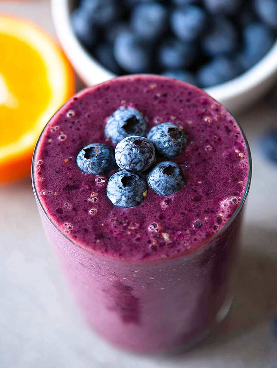 Szklanka koktajlu z jagodami na wierzchu.