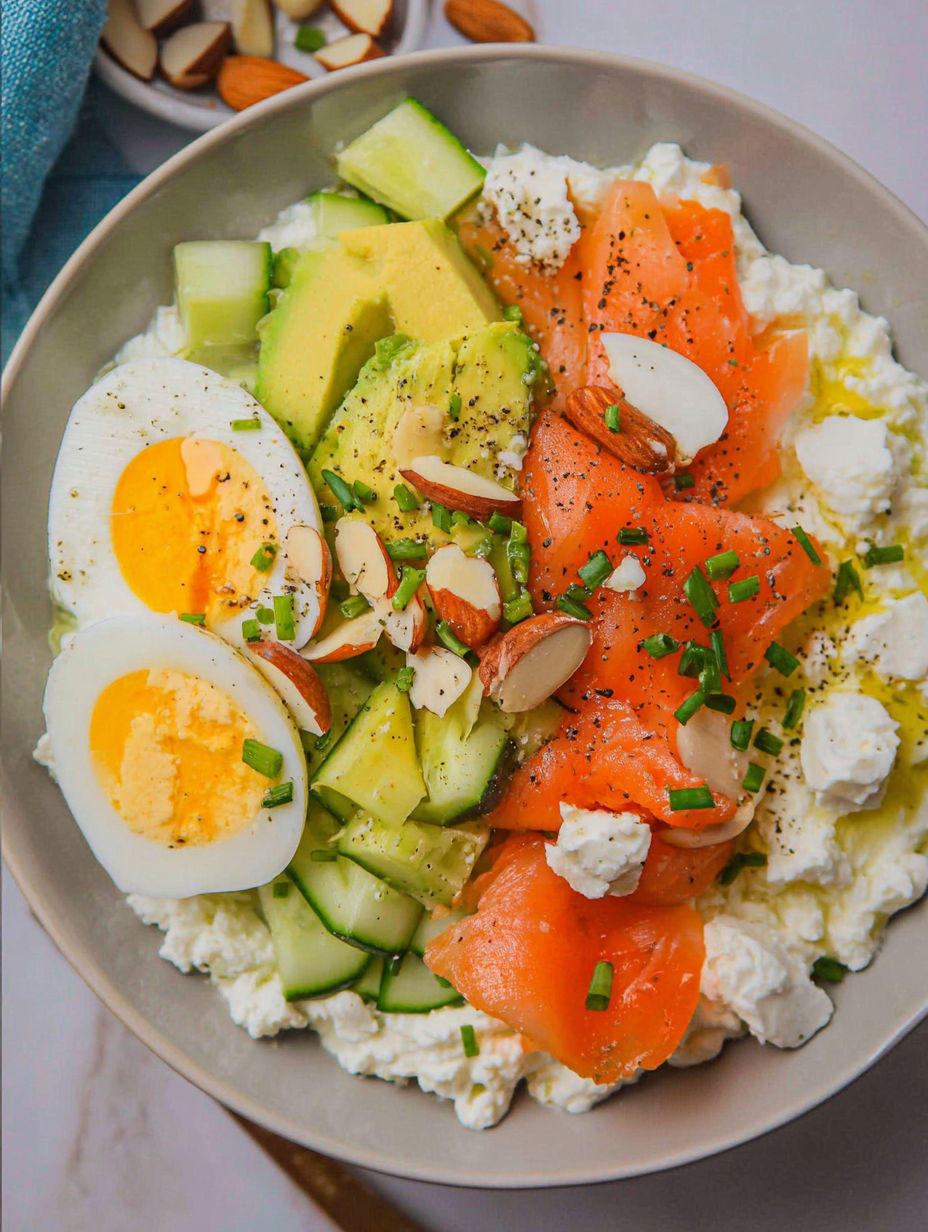 Talerz jedzenia z jajkami, ogórkami, awokado i wędzonym łososiem.