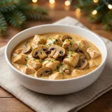 A bowl of chicken soup with mushrooms and herbs.