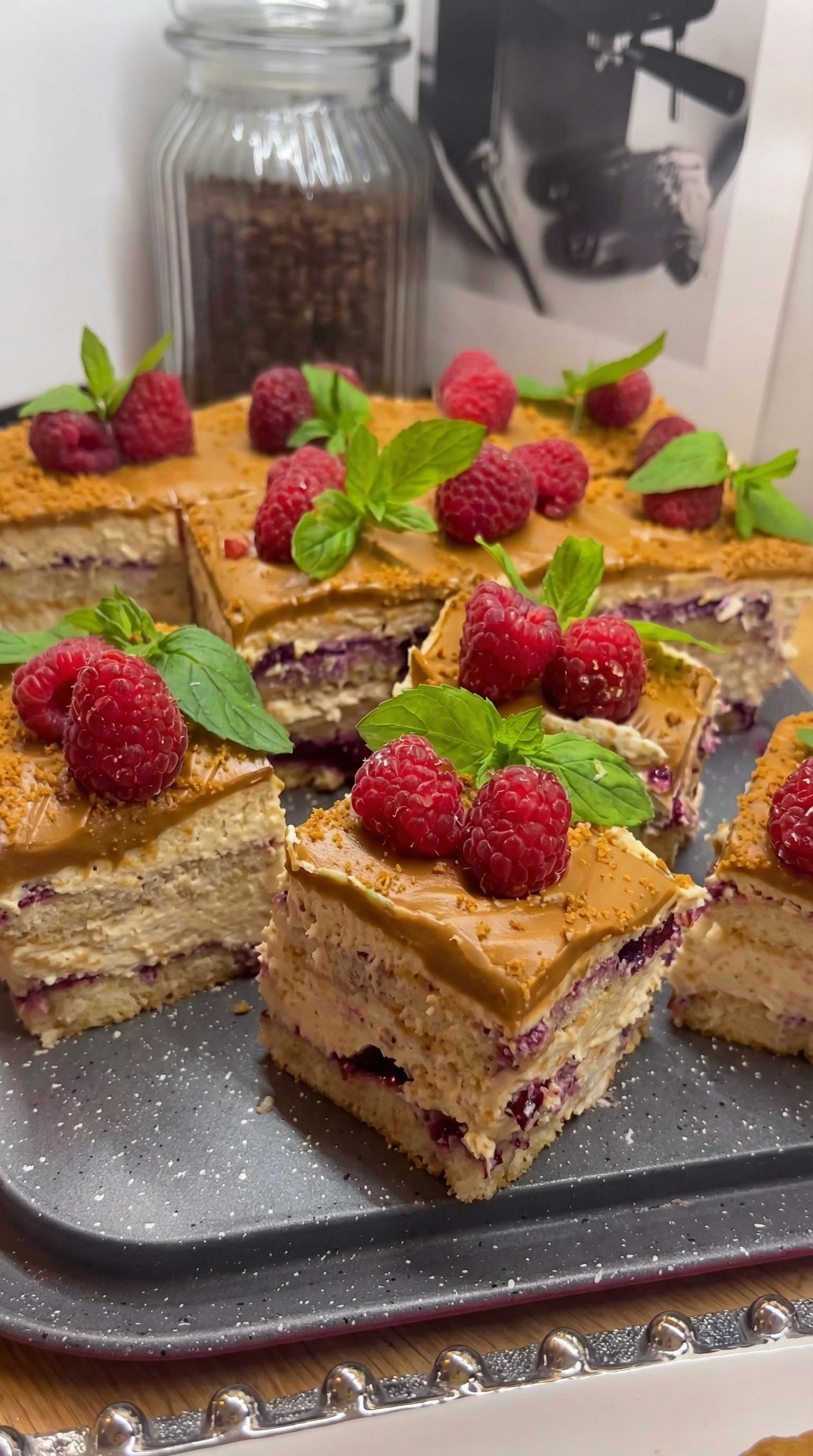 A slice of tiramisu lotus cake with raspberries on top.