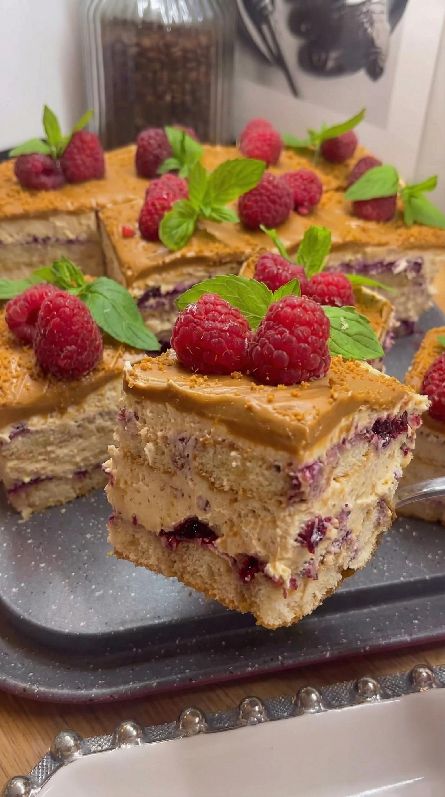 A slice of tiramisu lotus cake with raspberries on top.