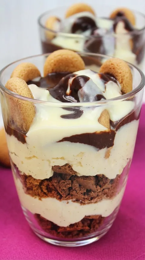 A glass of dessert with cookie crumbs and chocolate.
