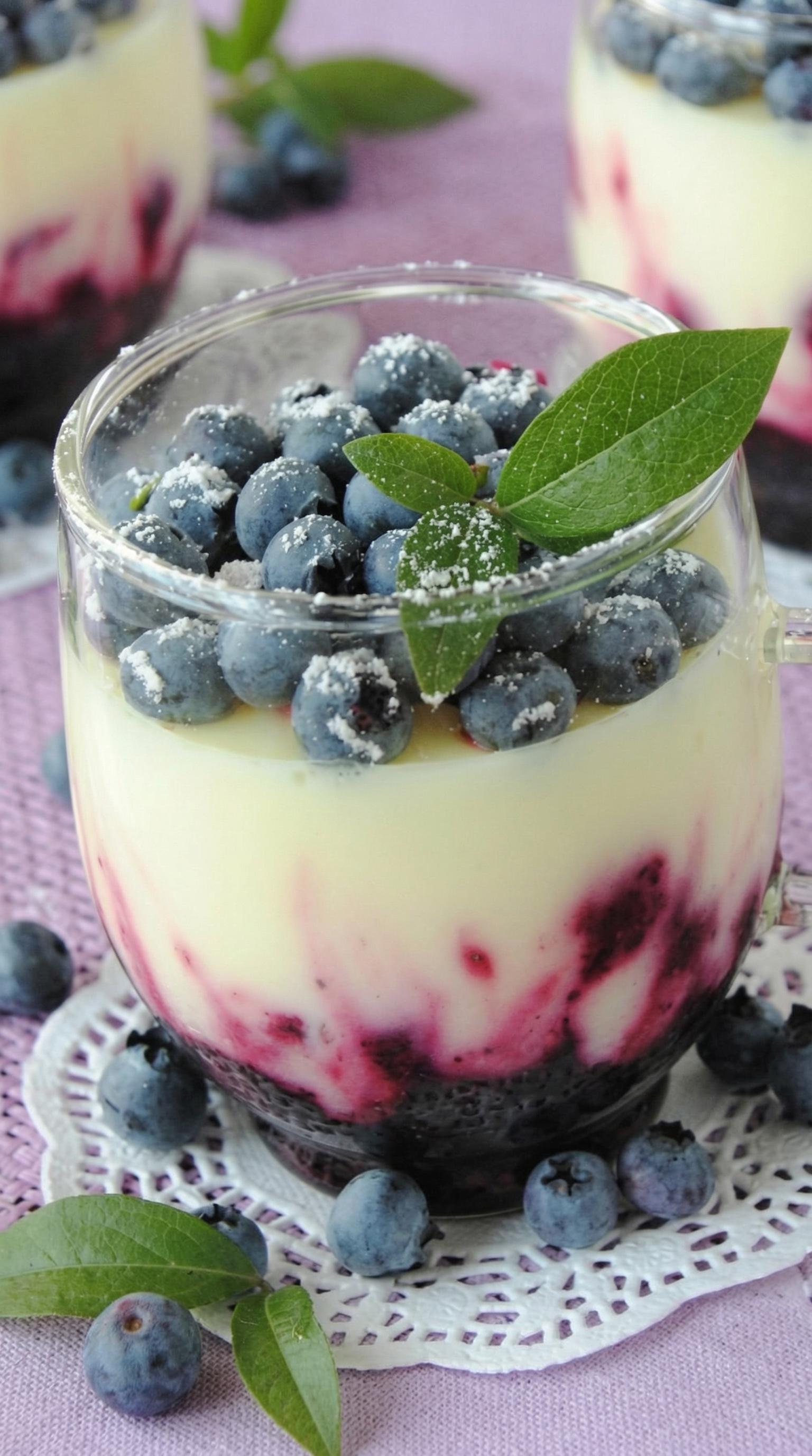 A glass of blueberry yogurt with a blueberry on top.