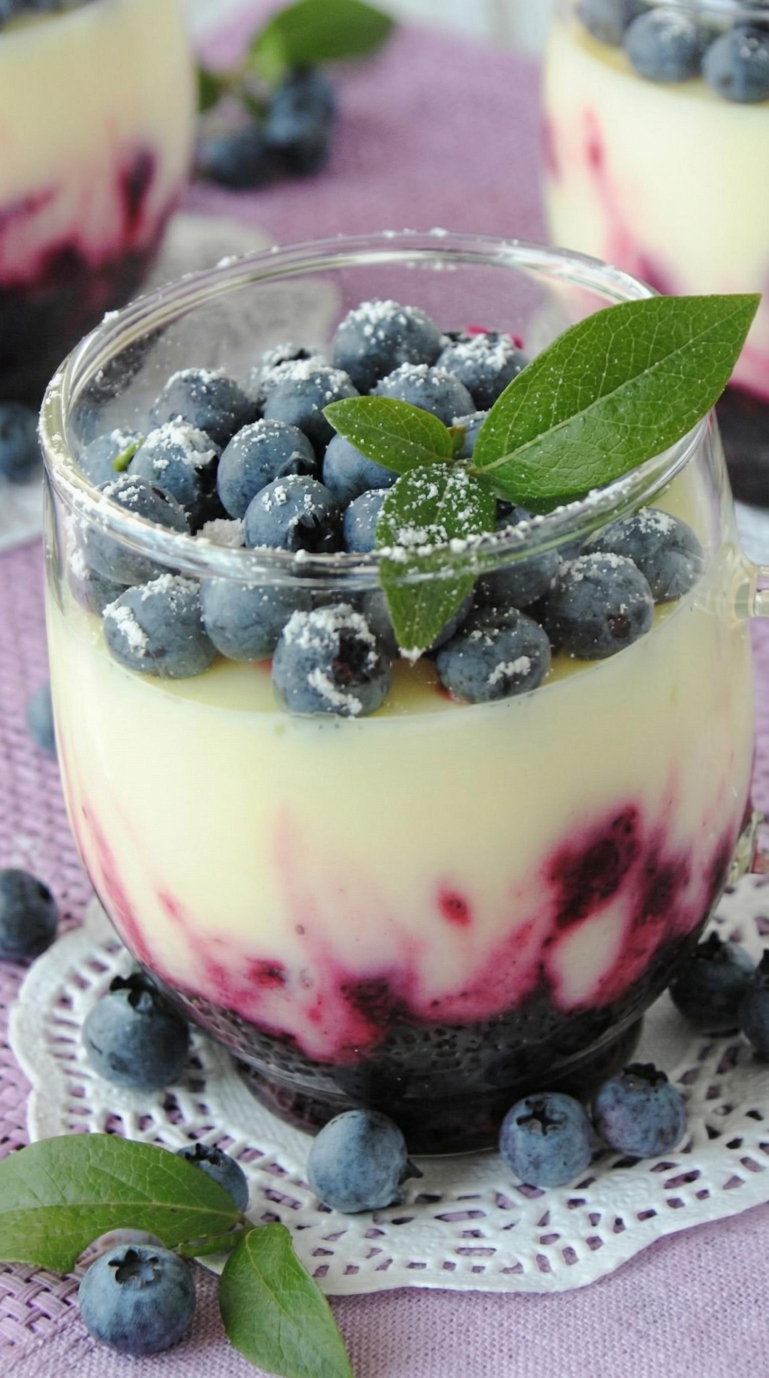 A glass of blueberry dessert with powdered sugar on top.