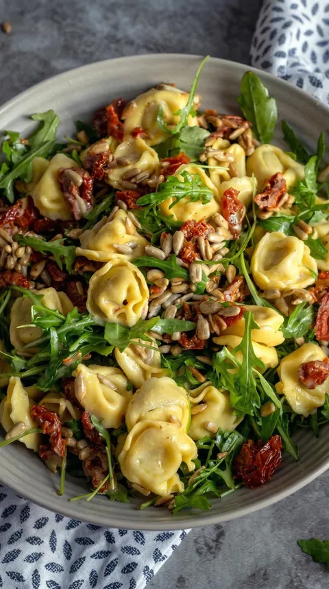 A bowl of pasta with spinach and pine nuts.