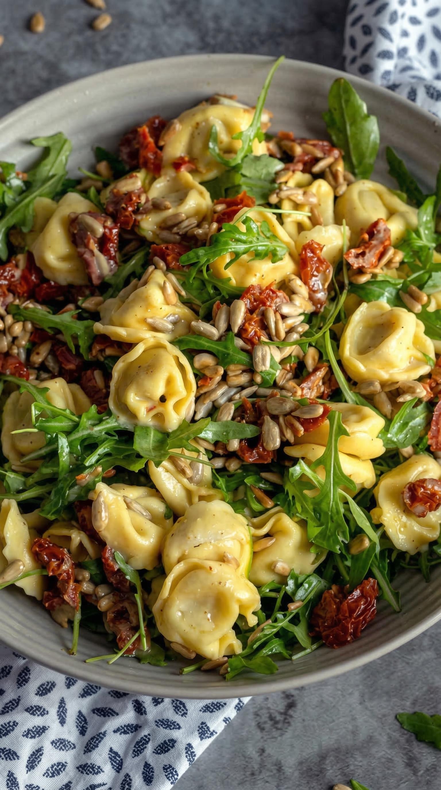 A bowl of pasta with spinach and pine nuts.