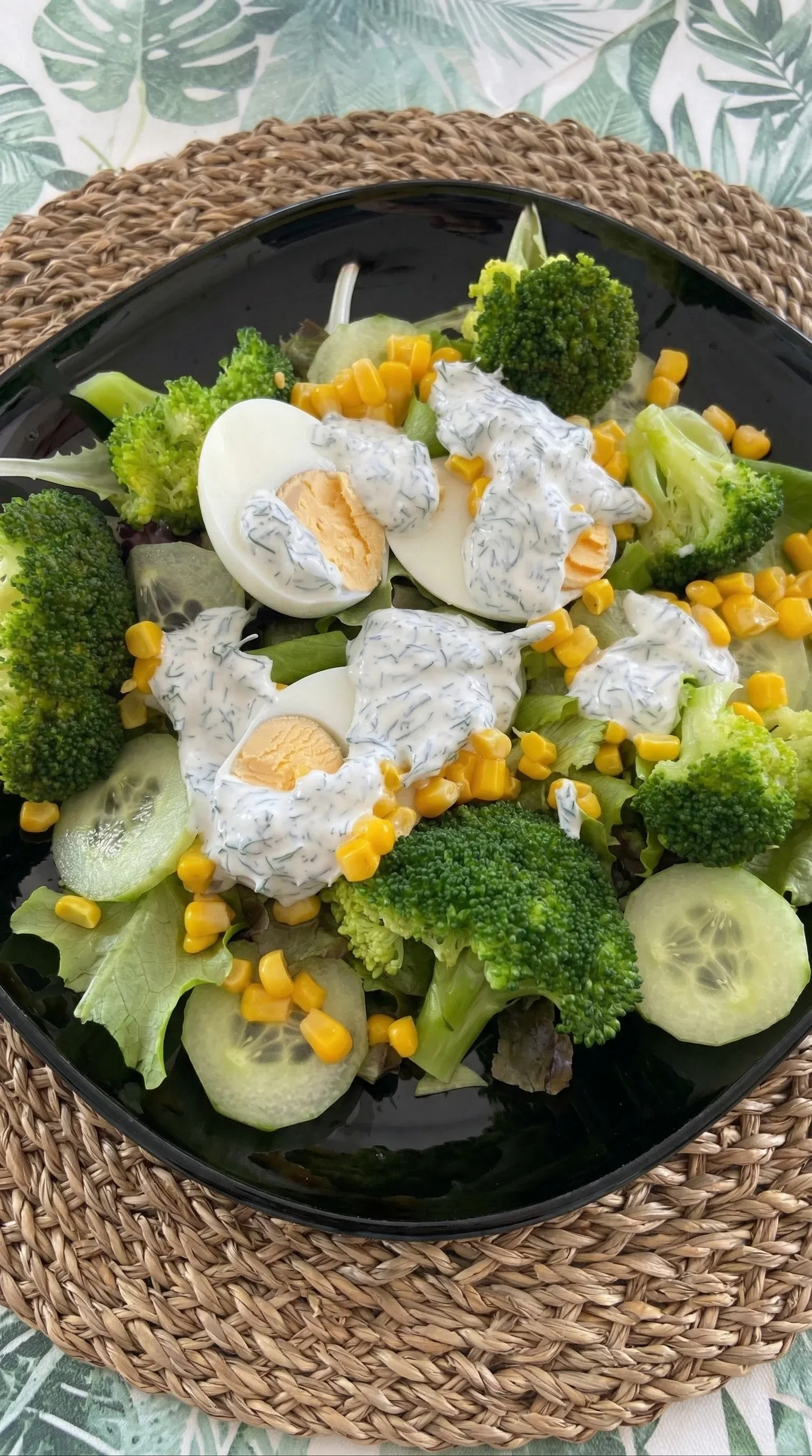 A salad with broccoli, corn, and eggs.