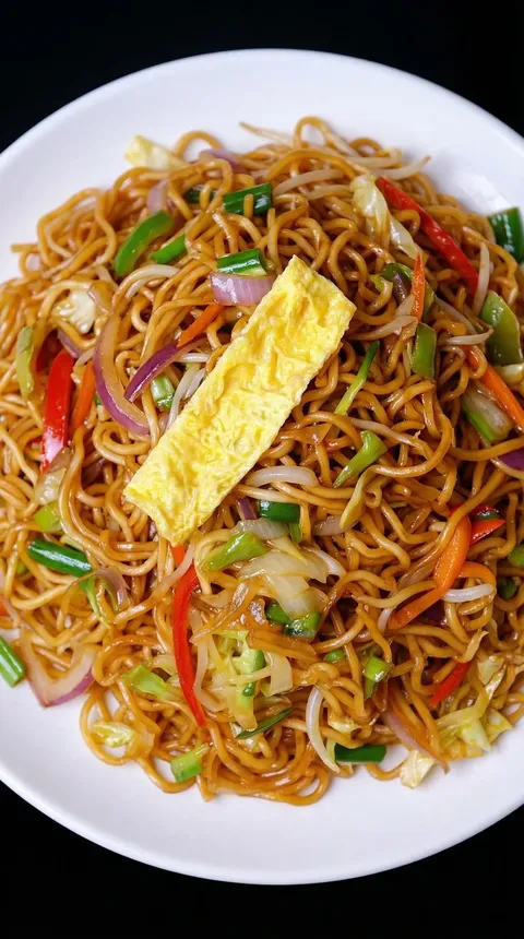 A plate of noodles with vegetables and a fried egg on top.
