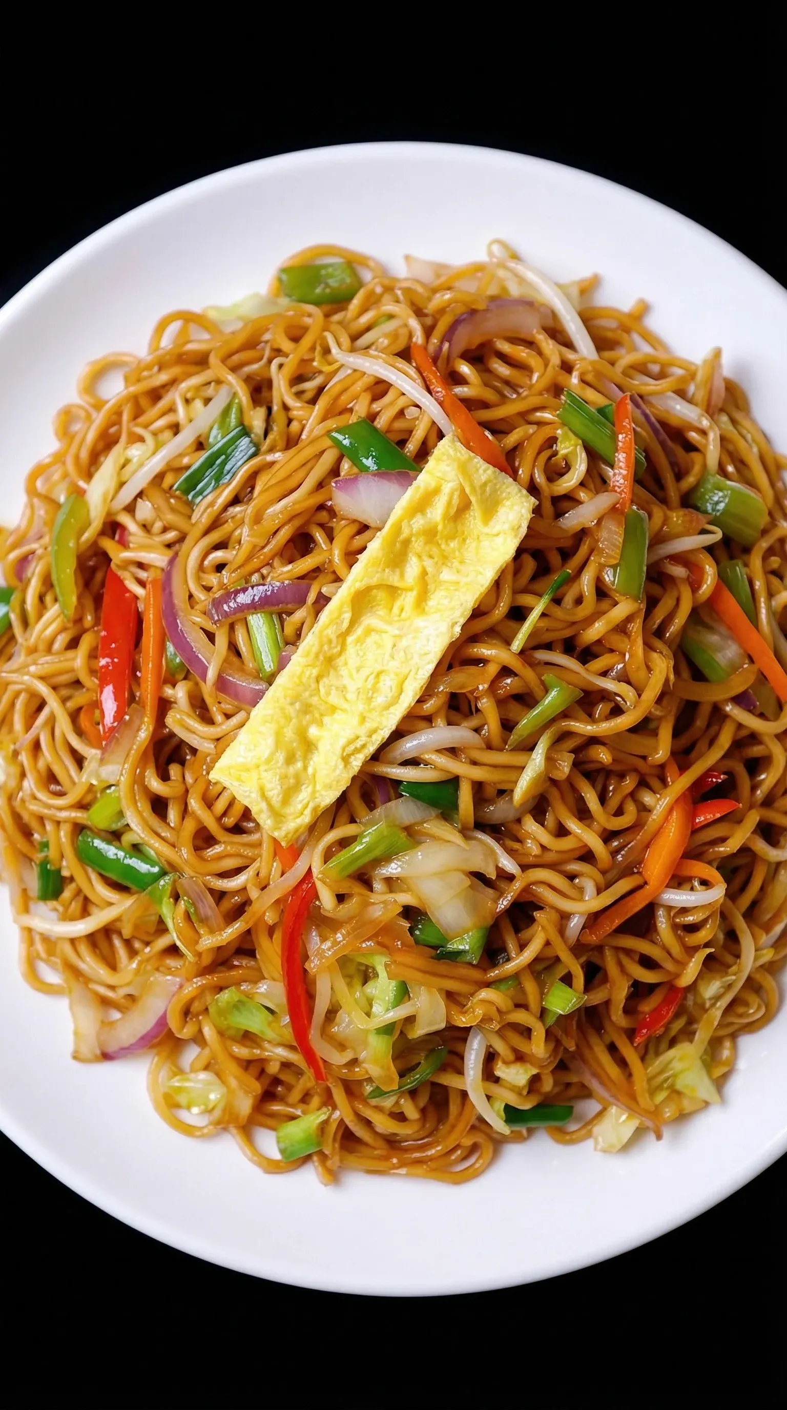 A plate of noodles with vegetables and a fried egg on top.