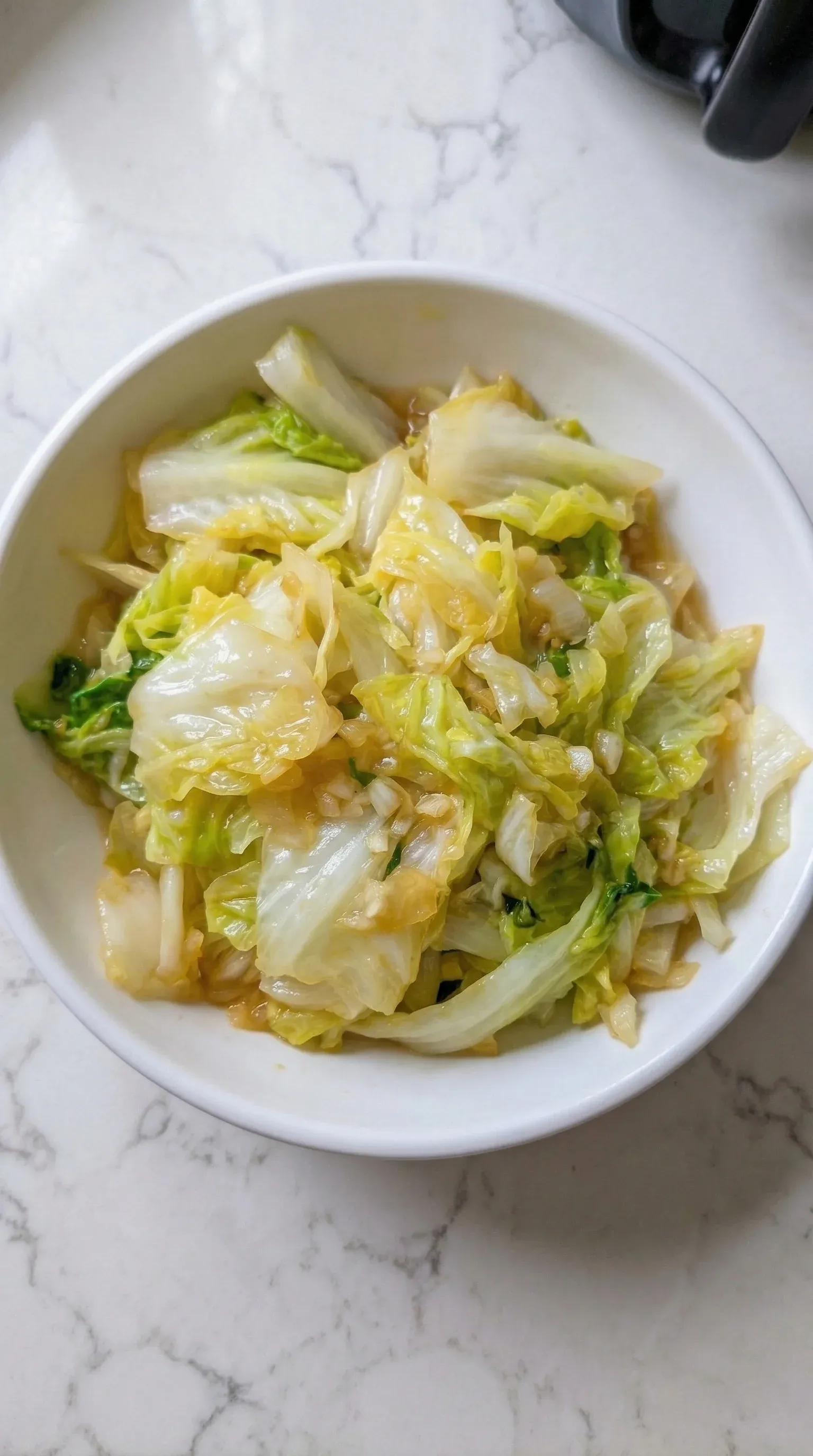 A bowl of cabbage with a white plate.