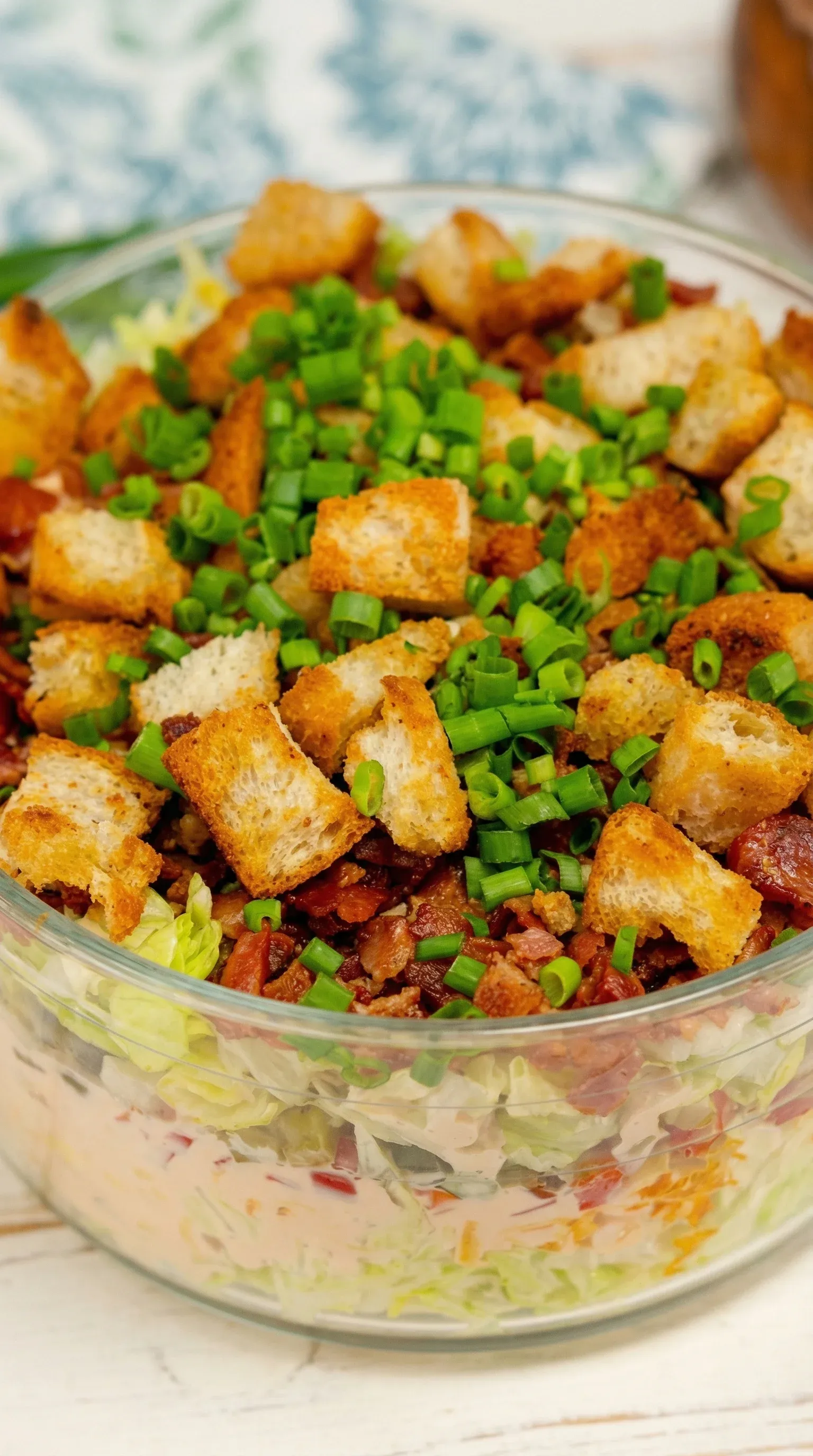 A bowl of salad with toast and bacon.