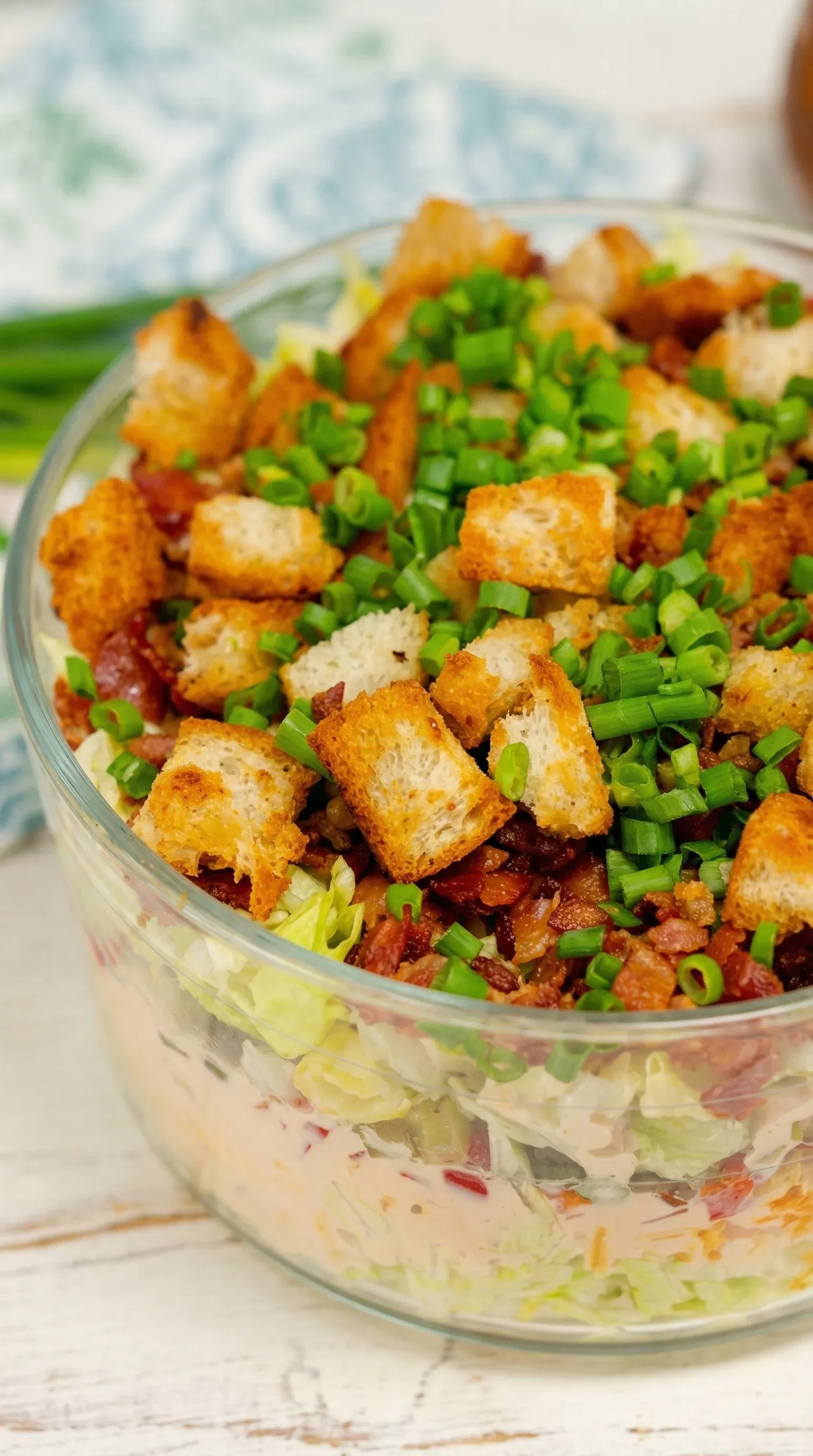 A bowl of salad with bacon, lettuce, and tomatoes.