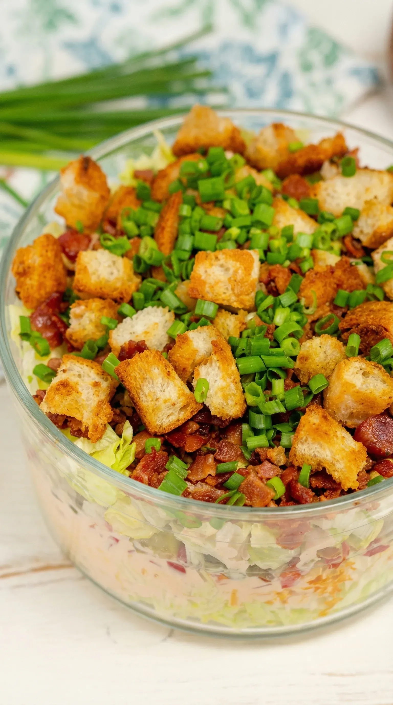 A bowl of salad with bacon and toast.
