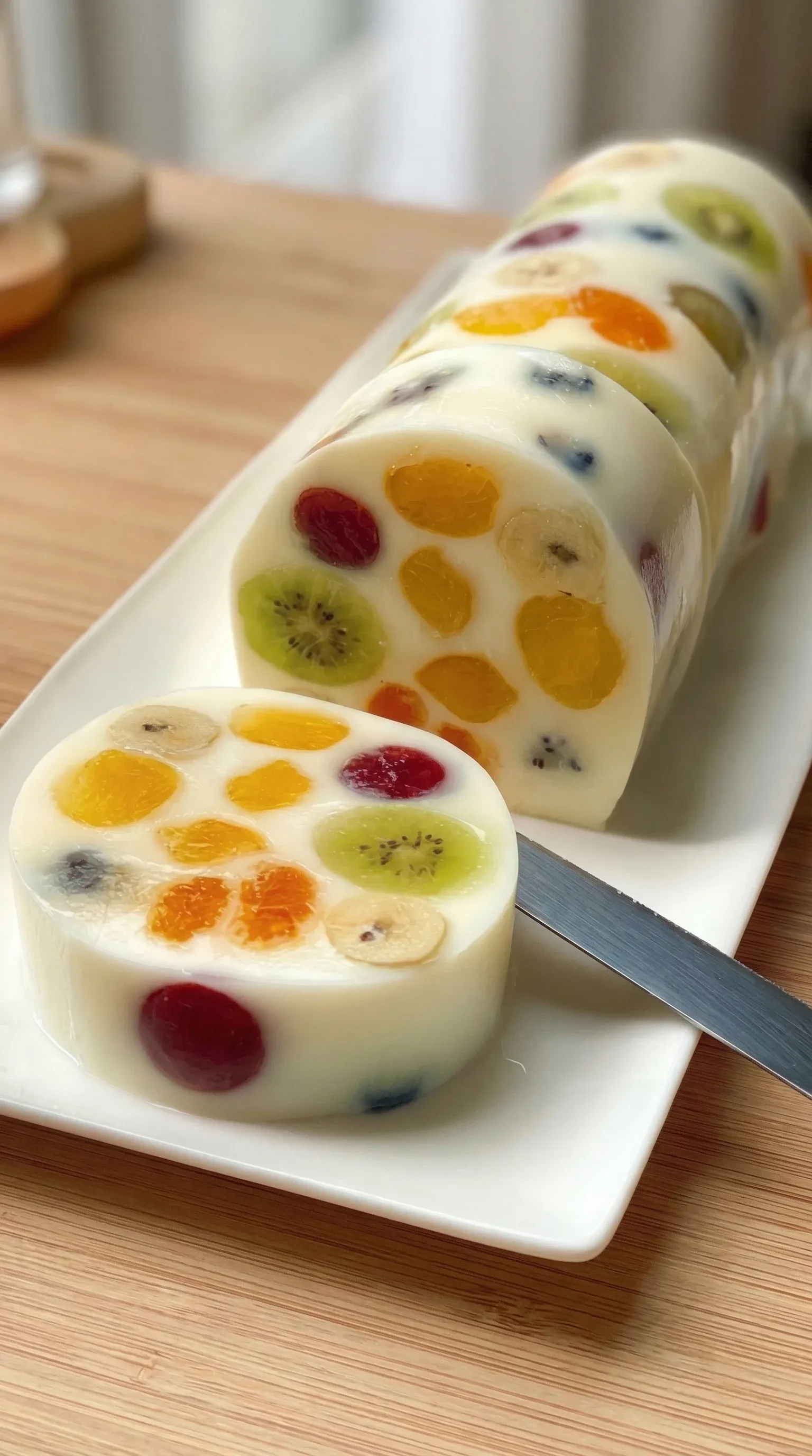A white plate with a slice of fruit roll cake.