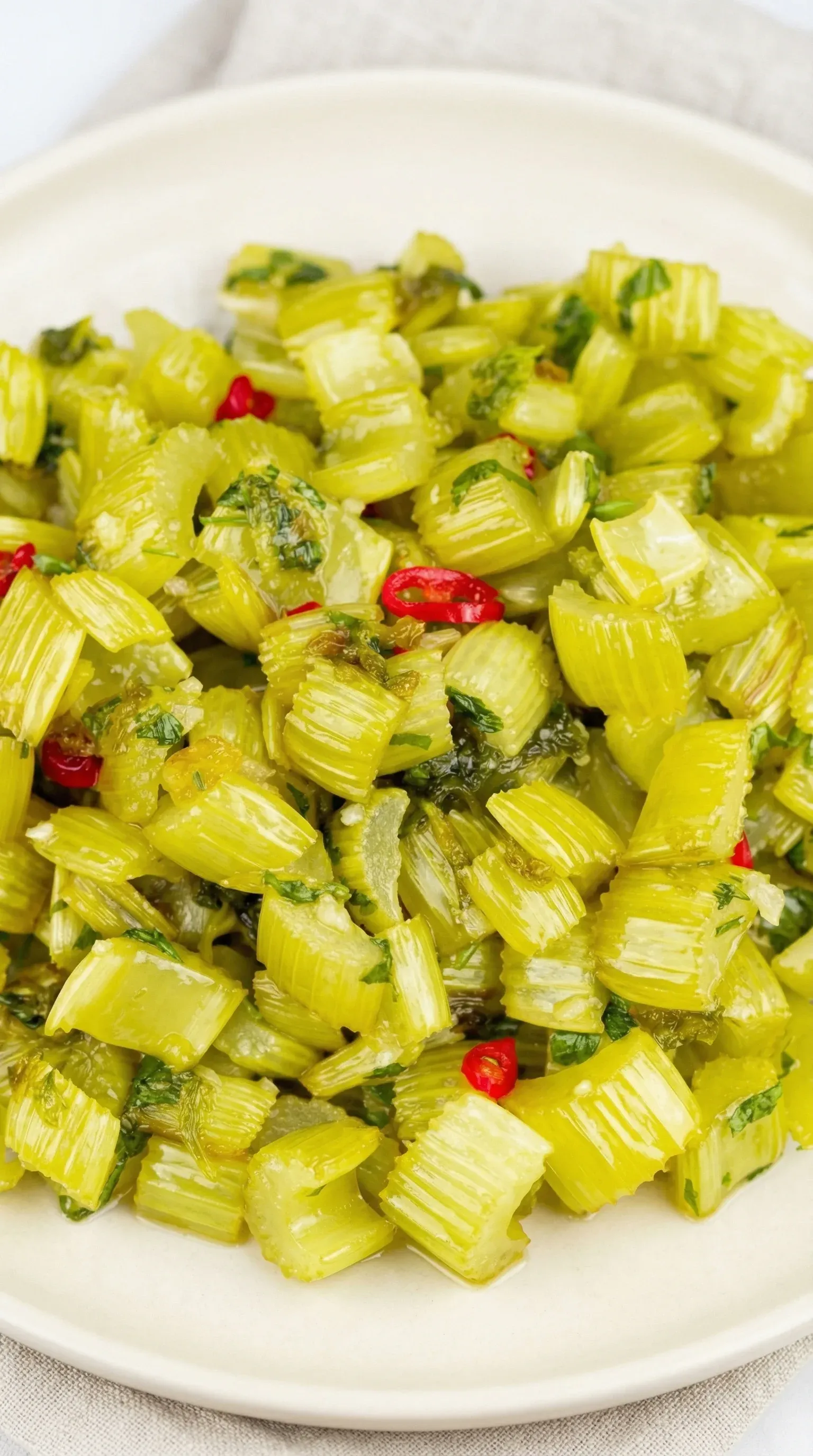 A plate of green vegetables with red peppers.