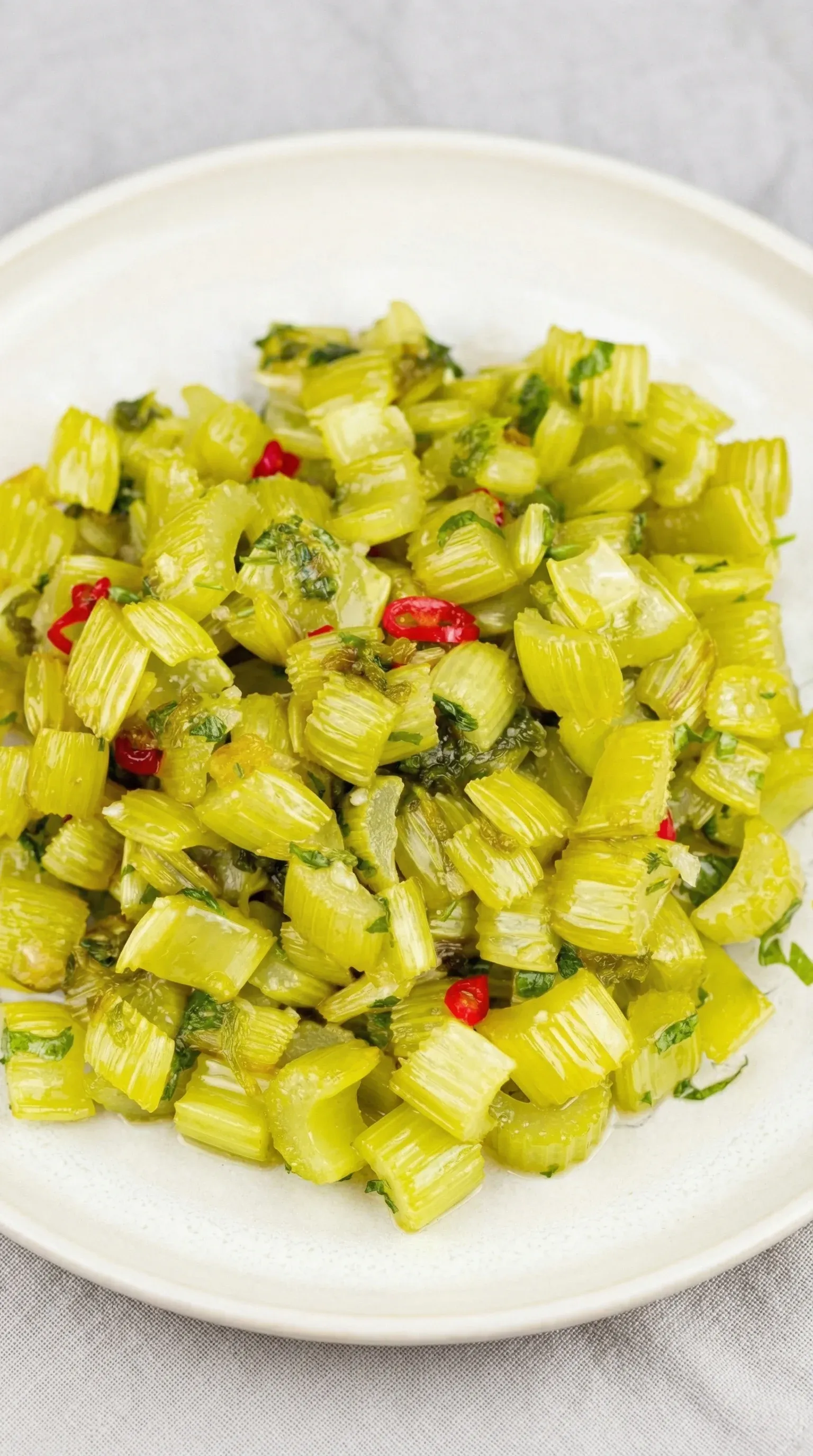 A plate of green vegetables with red peppers.