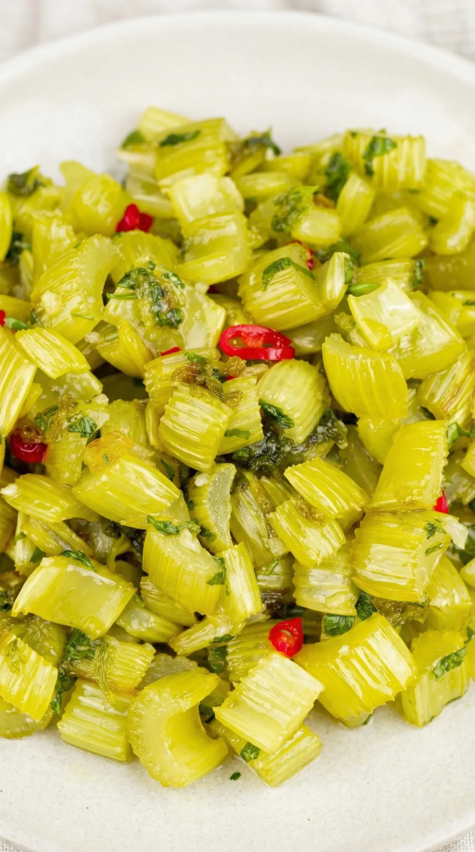 A pile of green vegetables with red peppers.