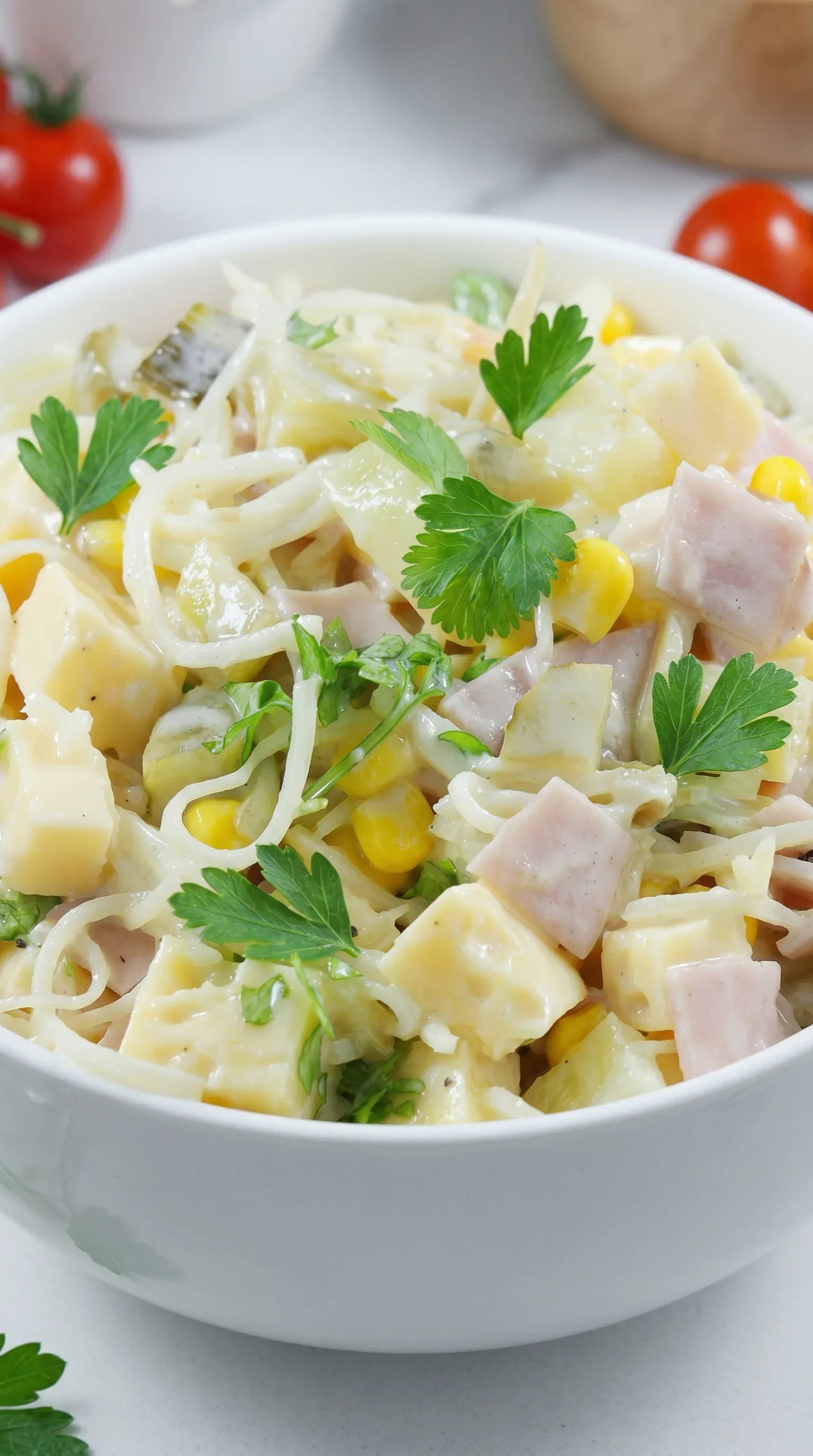 A bowl of salad with noodles, corn, and ham.
