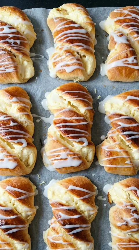 A tray of drożdżówki with white icing.