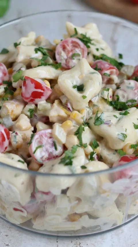 A bowl of salad with tomatoes, corn, and cheese.
