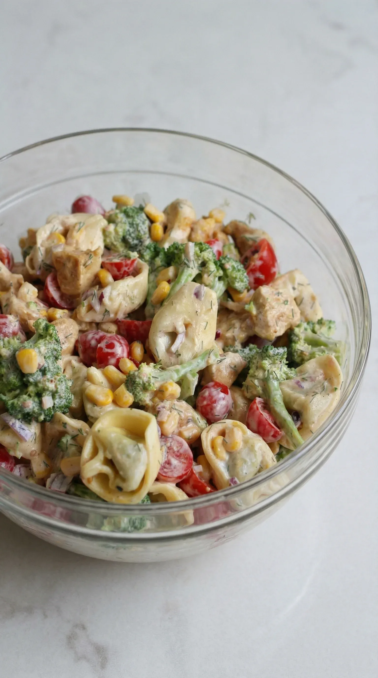 A bowl of salad with tomatoes, broccoli, and pasta.