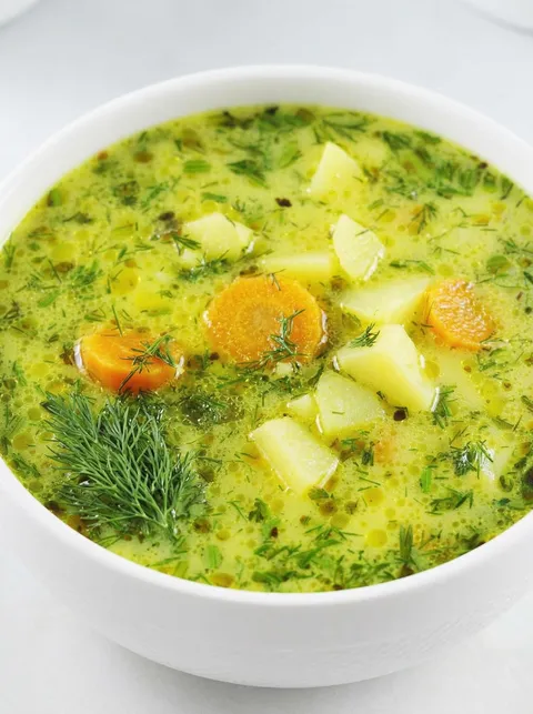 A bowl of soup with carrots and other vegetables.