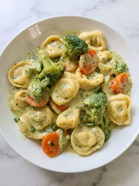 A bowl of pasta with broccoli and a creamy sauce.