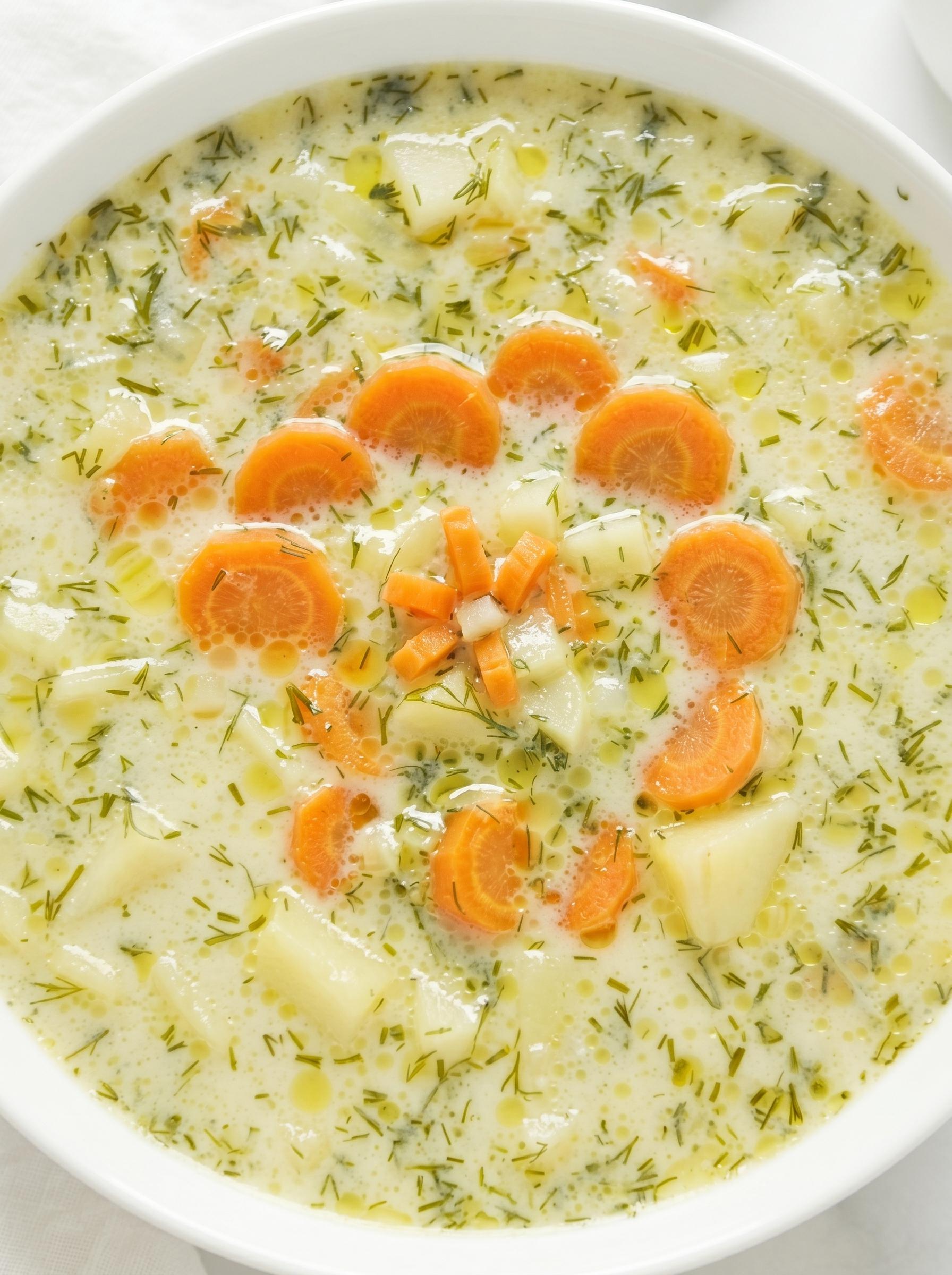 A bowl of soup with carrots and parsley.