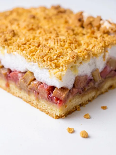 A slice of pie with white frosting and red fruit.