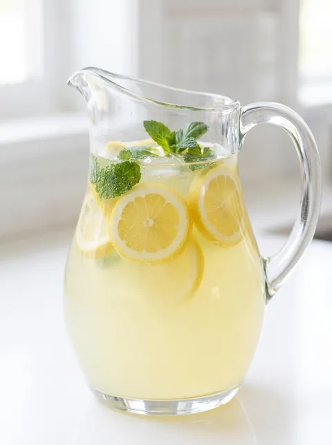 A pitcher of lemonade with lemon slices in it.