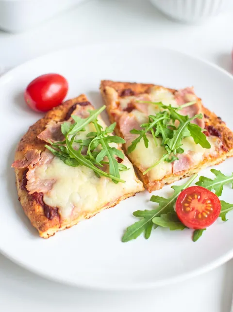A slice of pizza with greens on top.