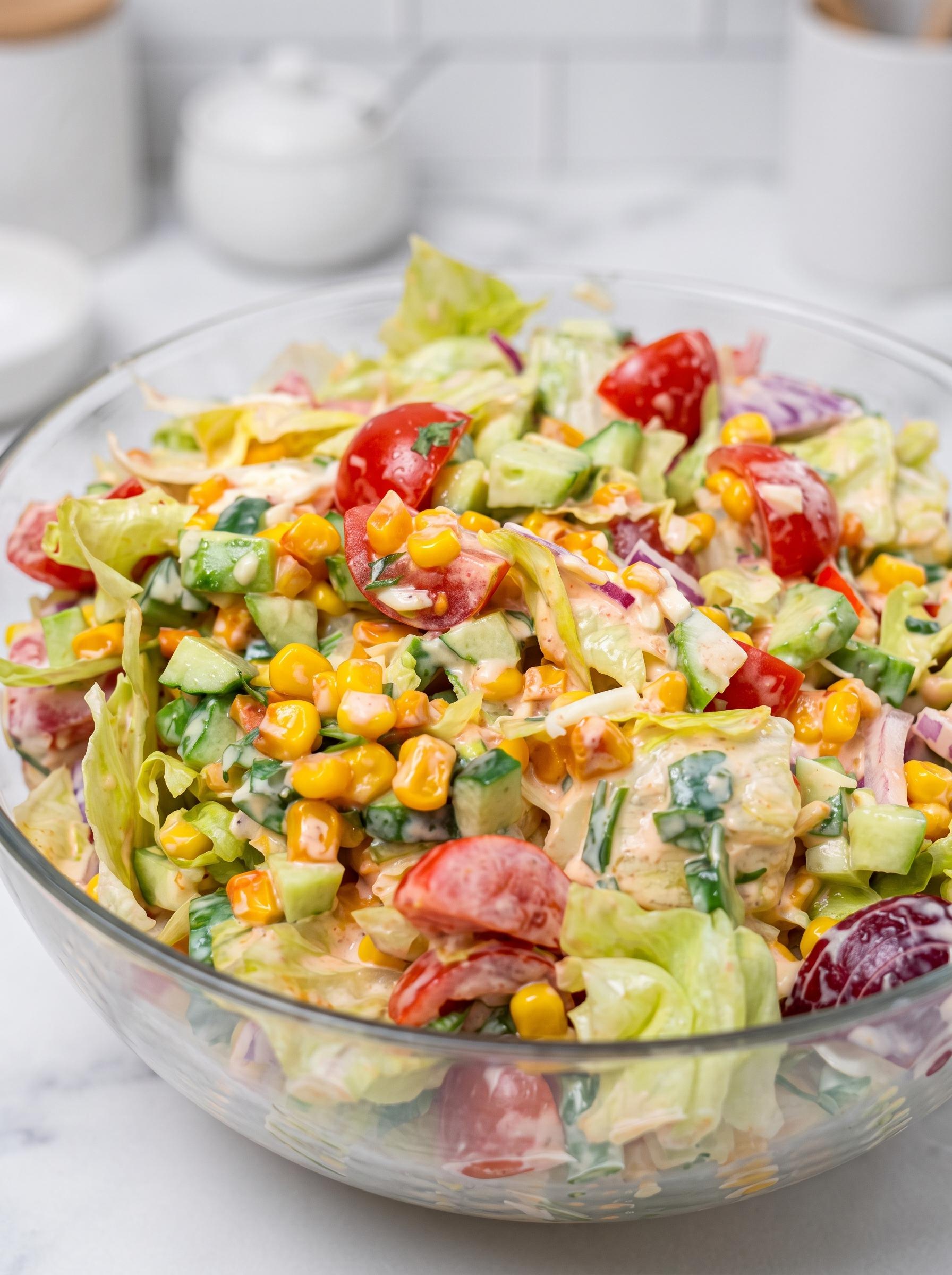 A bowl of salad with tomatoes, lettuce, and corn.