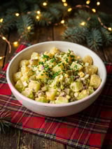 A bowl of salad with potatoes, corn, and green onions.