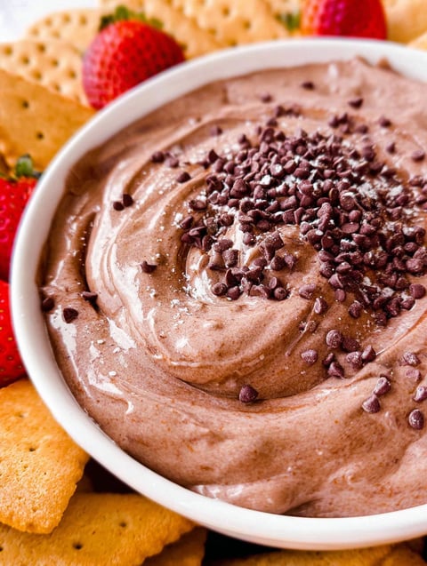 Miseczka kremowego dipu brownie z kawałkami czekolady na wierzchu.