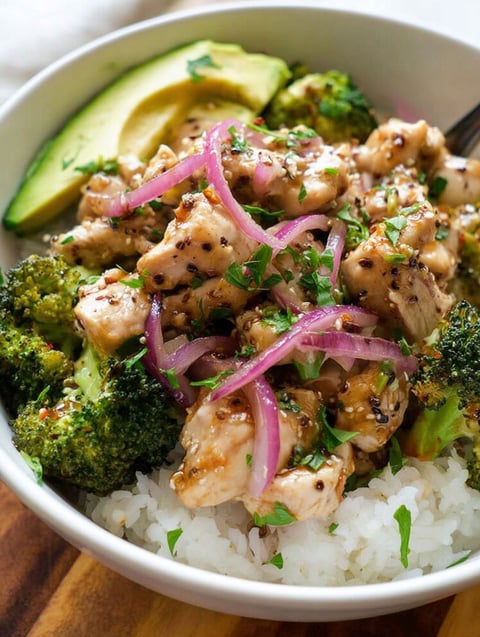 A bowl of chicken with broccoli and onions.