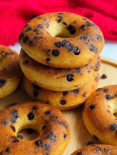 Donuty z kawałkami czekolady ułożone na drewnianej desce.